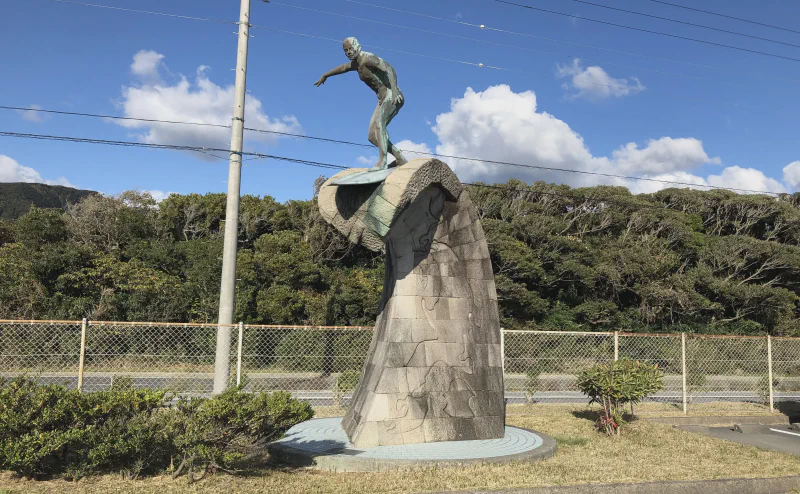 波を模した石積みの上に立つサーファーの銅像